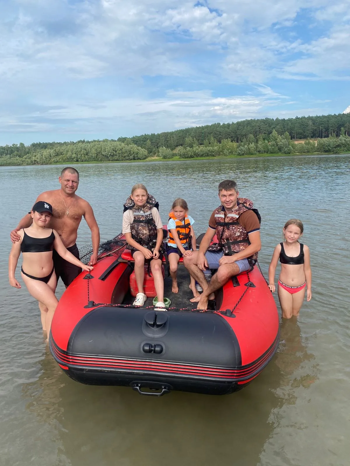 Семья позирует у красной лодки KITT BOATS на мелководье