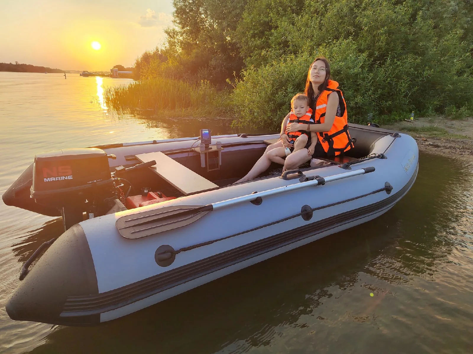 Взрослый с ребёнком в серой моторной лодке KITT BOATS на закате